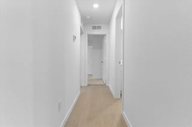 a view of a hallway with wooden floor and a bathroom