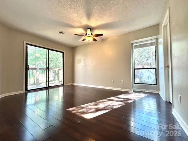 a view of an empty room with wooden floor closet and a window