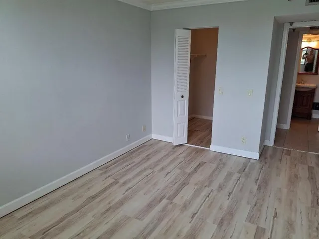 a view of an empty room with wooden floor and closet