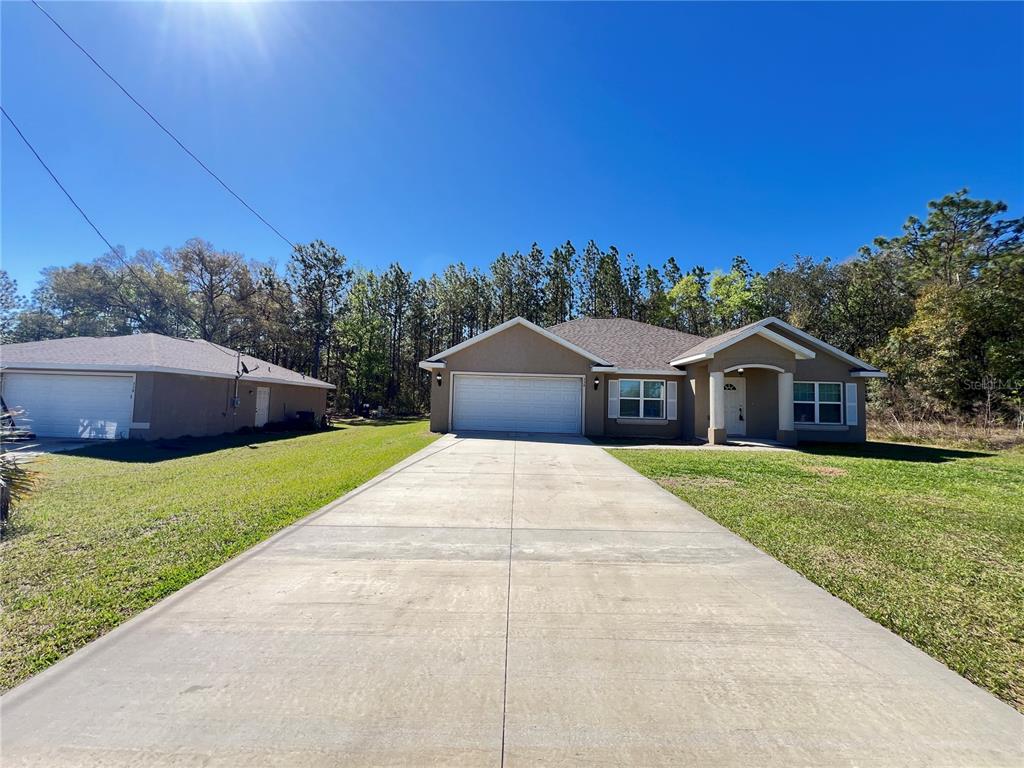 a front view of house with yard and trees in the background
