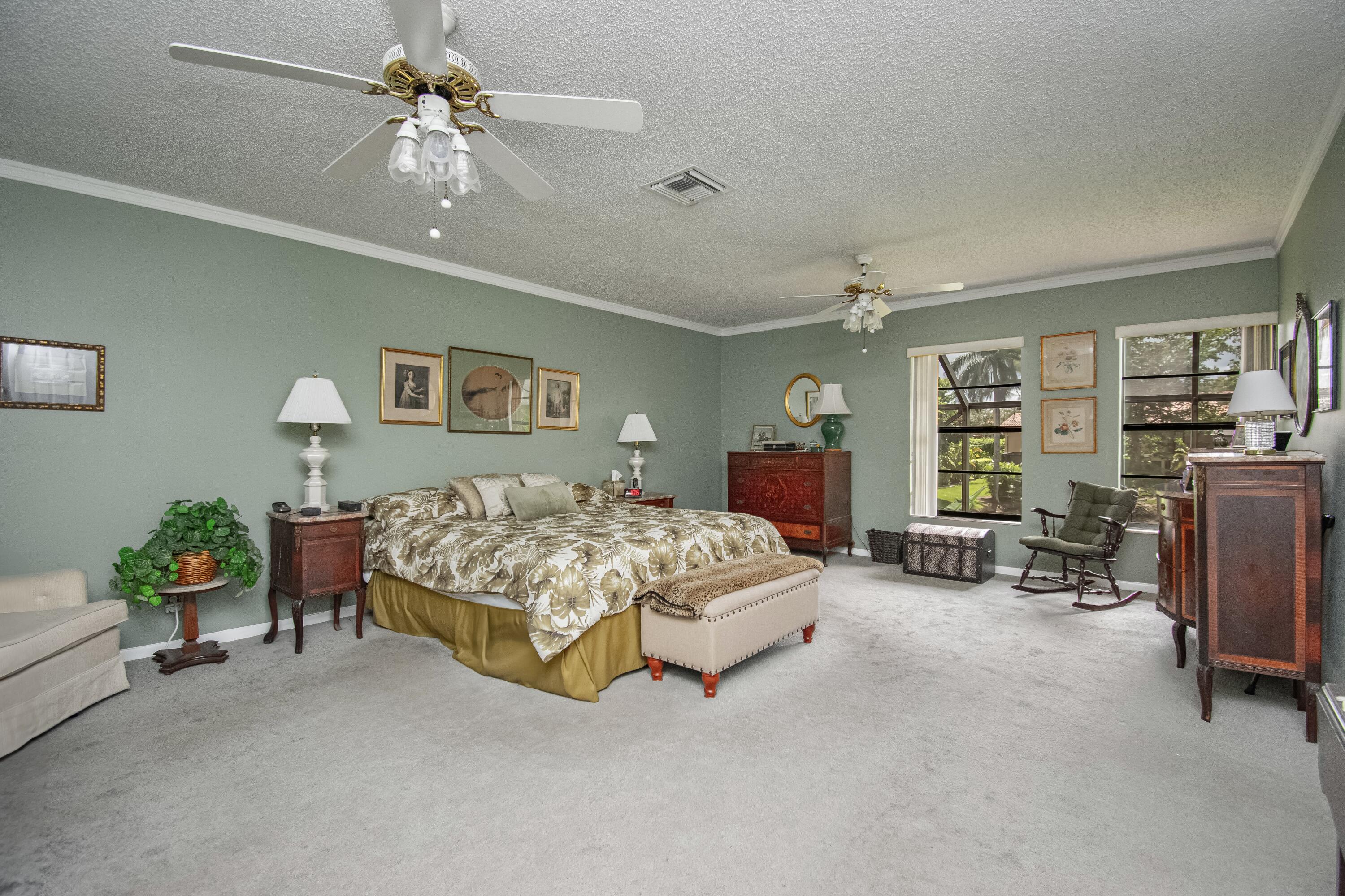 22066 Las Brisas Circle Boca Raton, FL 33433 - Photo 21 of 45 a spacious bedroom with a bed a couch and a chandelier