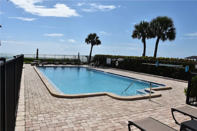 a view of a swimming pool with a table and chairs under an umbrella