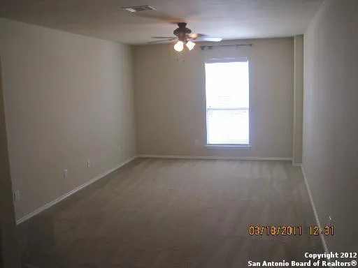an empty room with a window and a ceiling fan