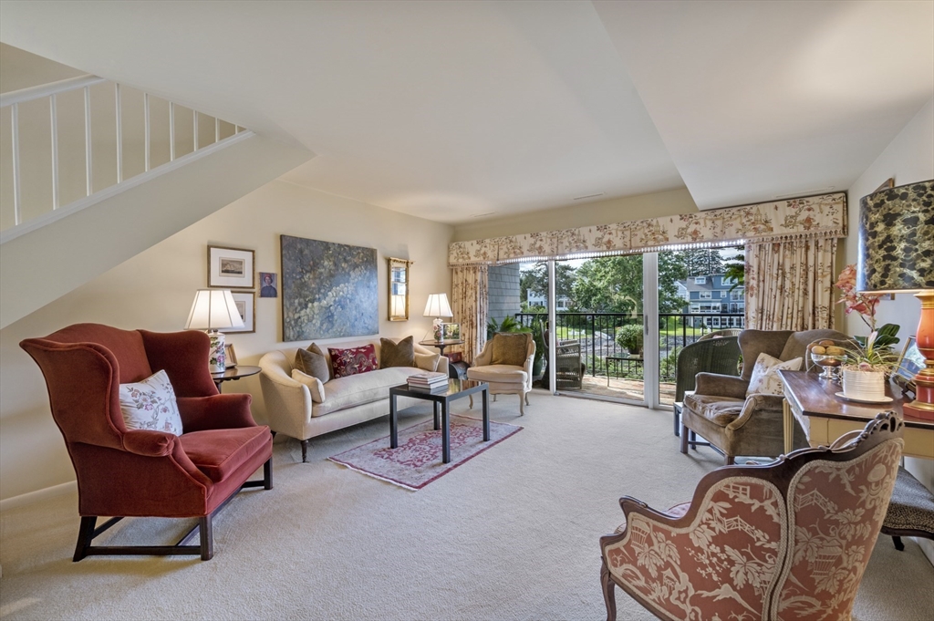 a living room with furniture large windows and wooden floor