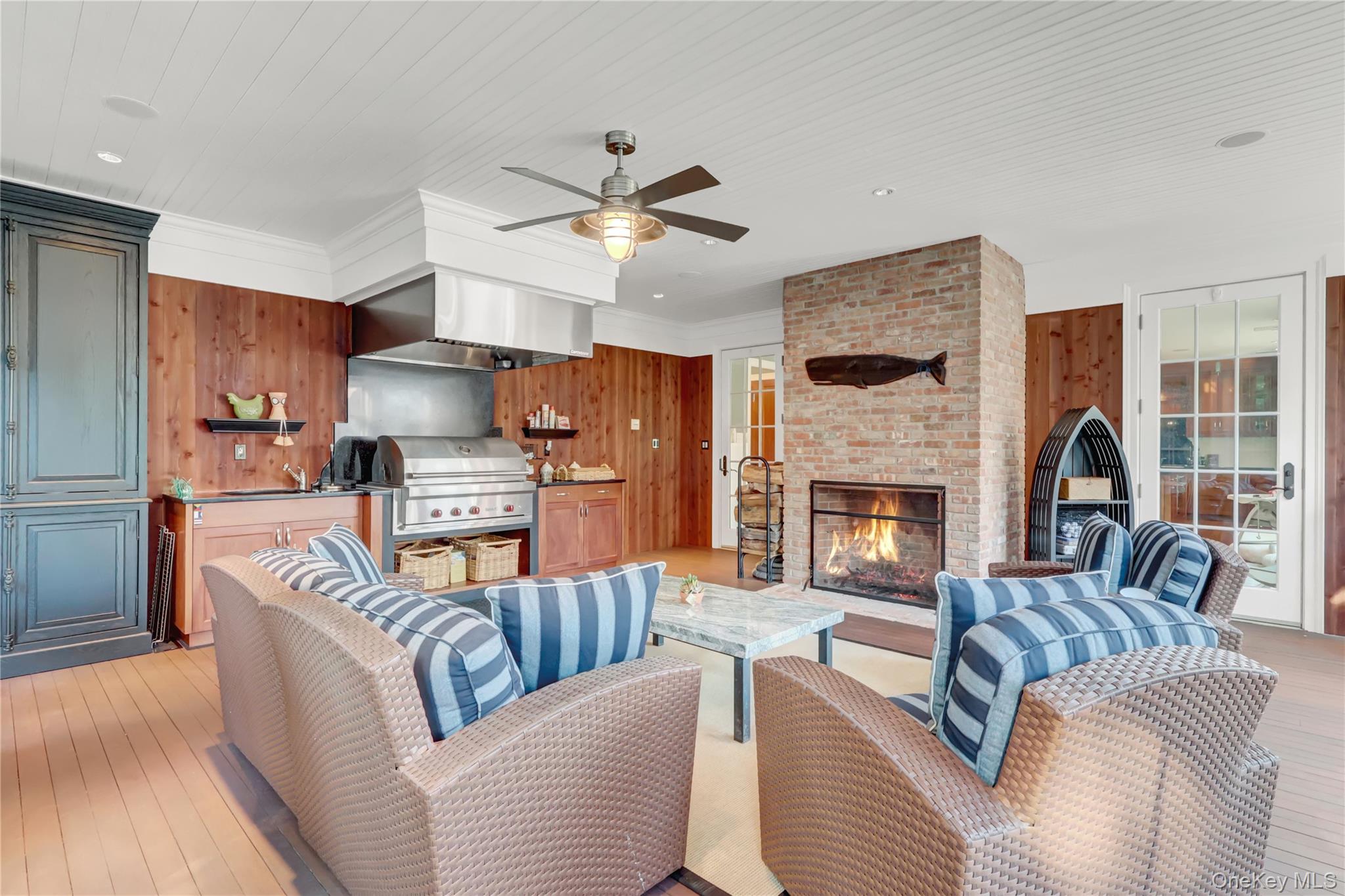 63 Dyke Road Setauket, NY 11733 - Photo 38 of 49 Living room with wood walls, a brick fireplace, light wood-style flooring, crown molding, and a ceiling fan