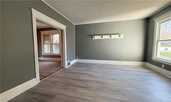 an empty room with wooden floor closet and windows