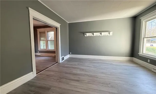 an empty room with wooden floor closet and windows