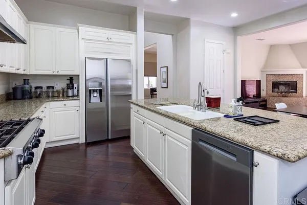 a kitchen with a sink a stove and chairs with wooden floor