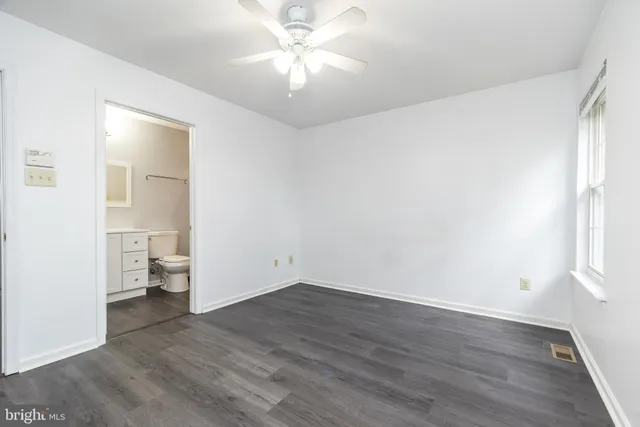 an empty room with wooden floor and a ceiling fan