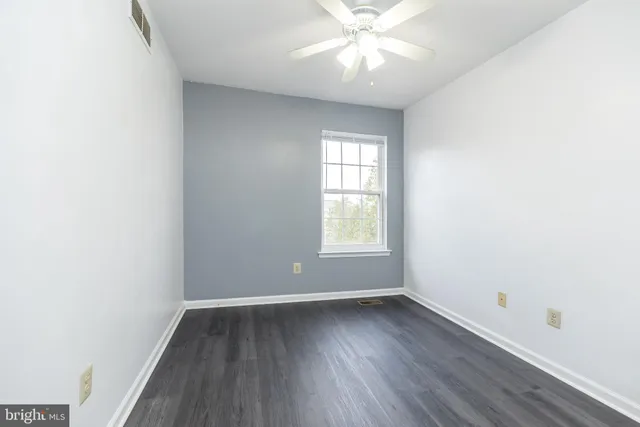 an empty room with wooden floor fan and windows