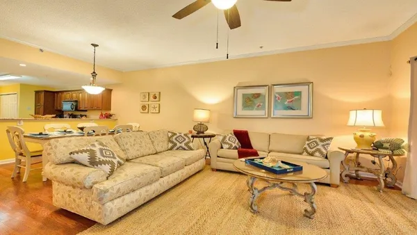 a living room with furniture kitchen view and a chandelier