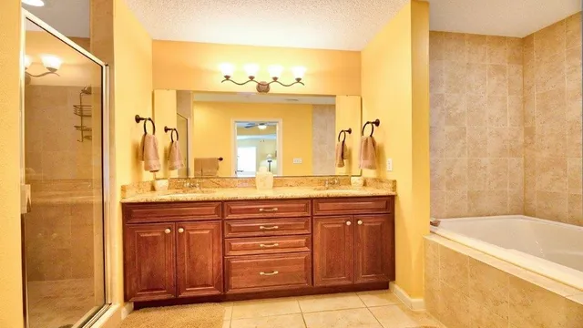 a bathroom with a granite countertop sink a mirror a bathtub and shower