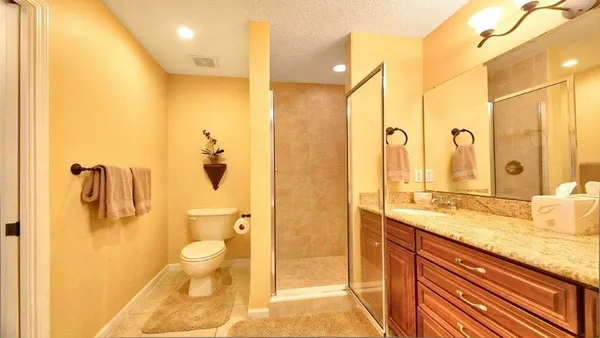 a bathroom with a granite countertop sink a toilet and shower