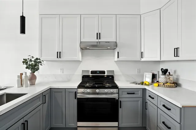 a kitchen with stainless steel appliances granite countertop white cabinets a stove a sink and dishwasher
