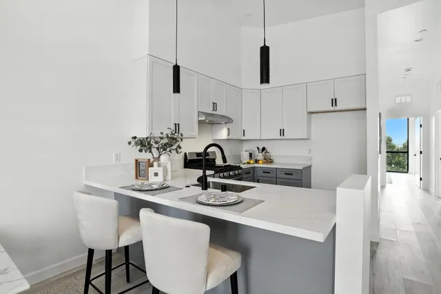 a kitchen with stainless steel appliances granite countertop a sink a stove a refrigerator and white cabinets with wooden floor