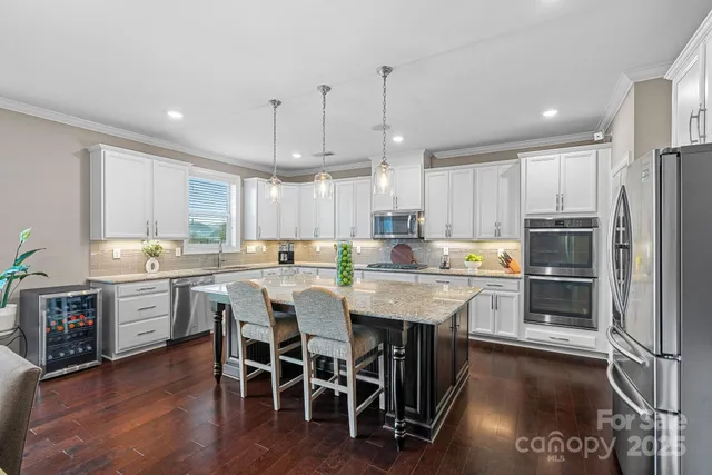a kitchen with stainless steel appliances kitchen island granite countertop a table chairs and a refrigerator