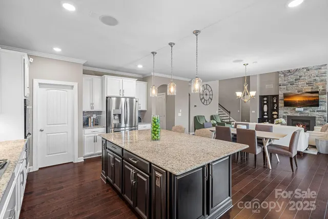 a kitchen with stainless steel appliances granite countertop a kitchen island a stove a table and chairs