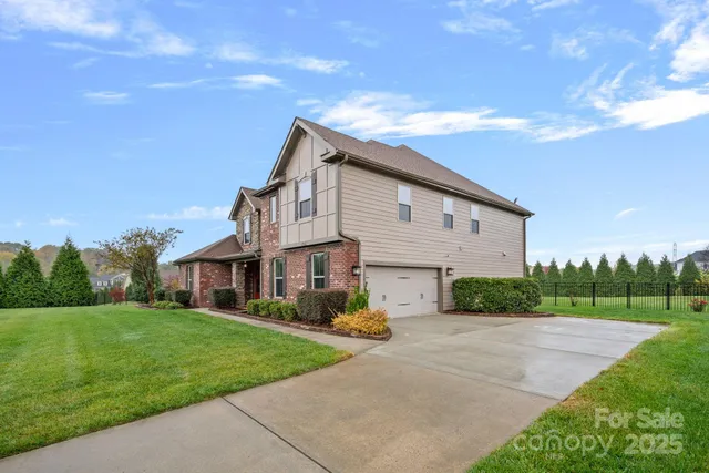 a view of a white house next to a yard with big trees