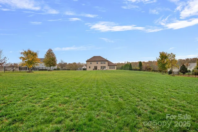 a view of a house with a big yard and large trees