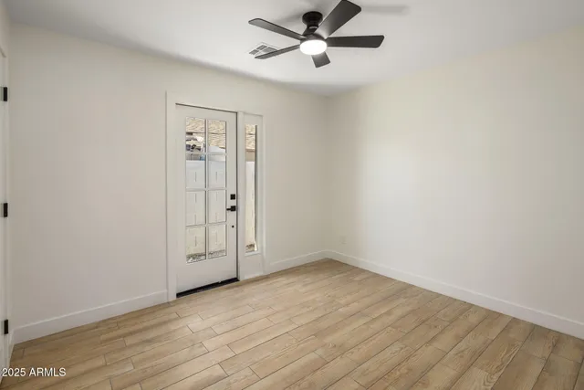 an empty room with wooden floor and windows