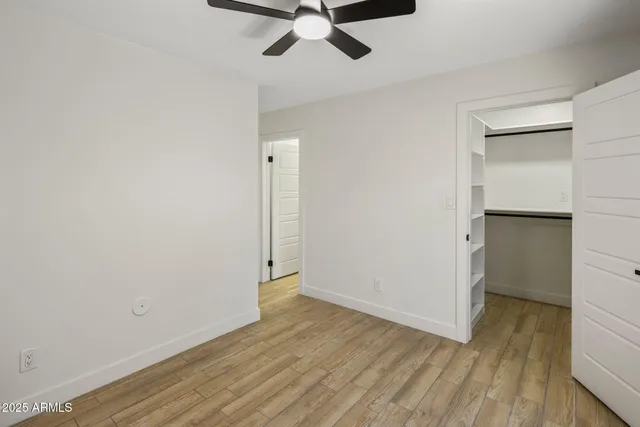 an empty room with wooden floor a ceiling fan