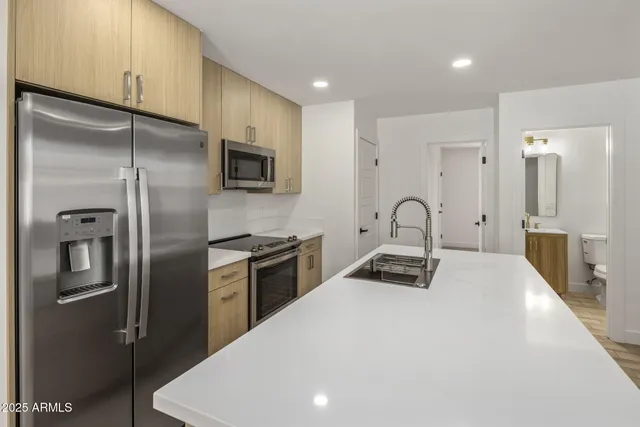 a kitchen with stainless steel appliances granite countertop a refrigerator a stove and a sink with wooden floor