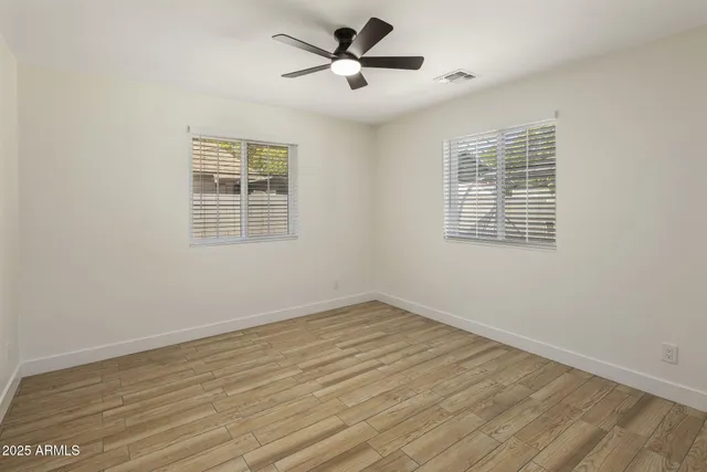 a view of empty room with wooden floor and fan