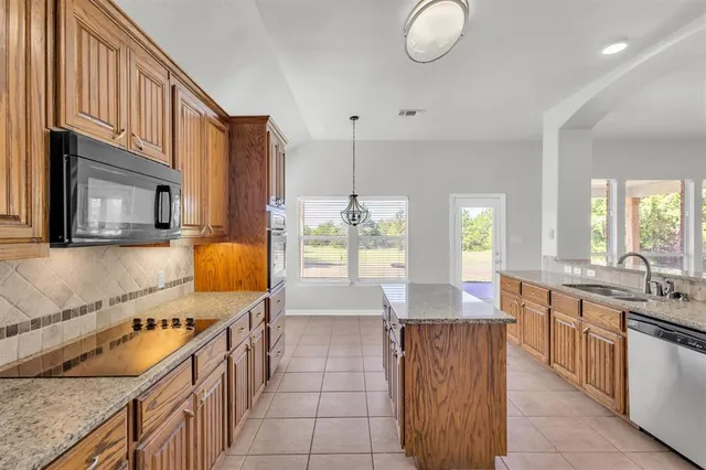 a kitchen with granite countertop a sink stove and cabinets