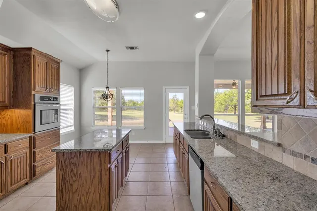 a kitchen with granite countertop a sink a counter top space and cabinets