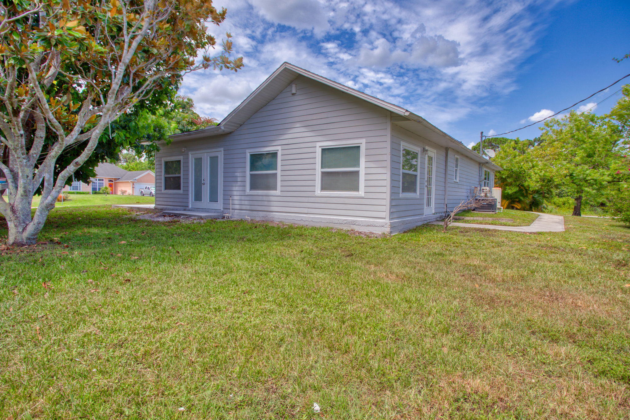 4302 Southwest Jaunt Road Port St. Lucie, FL 34953 - Photo 32 of 32 a view of a yard in front of a house with plants and large tree
