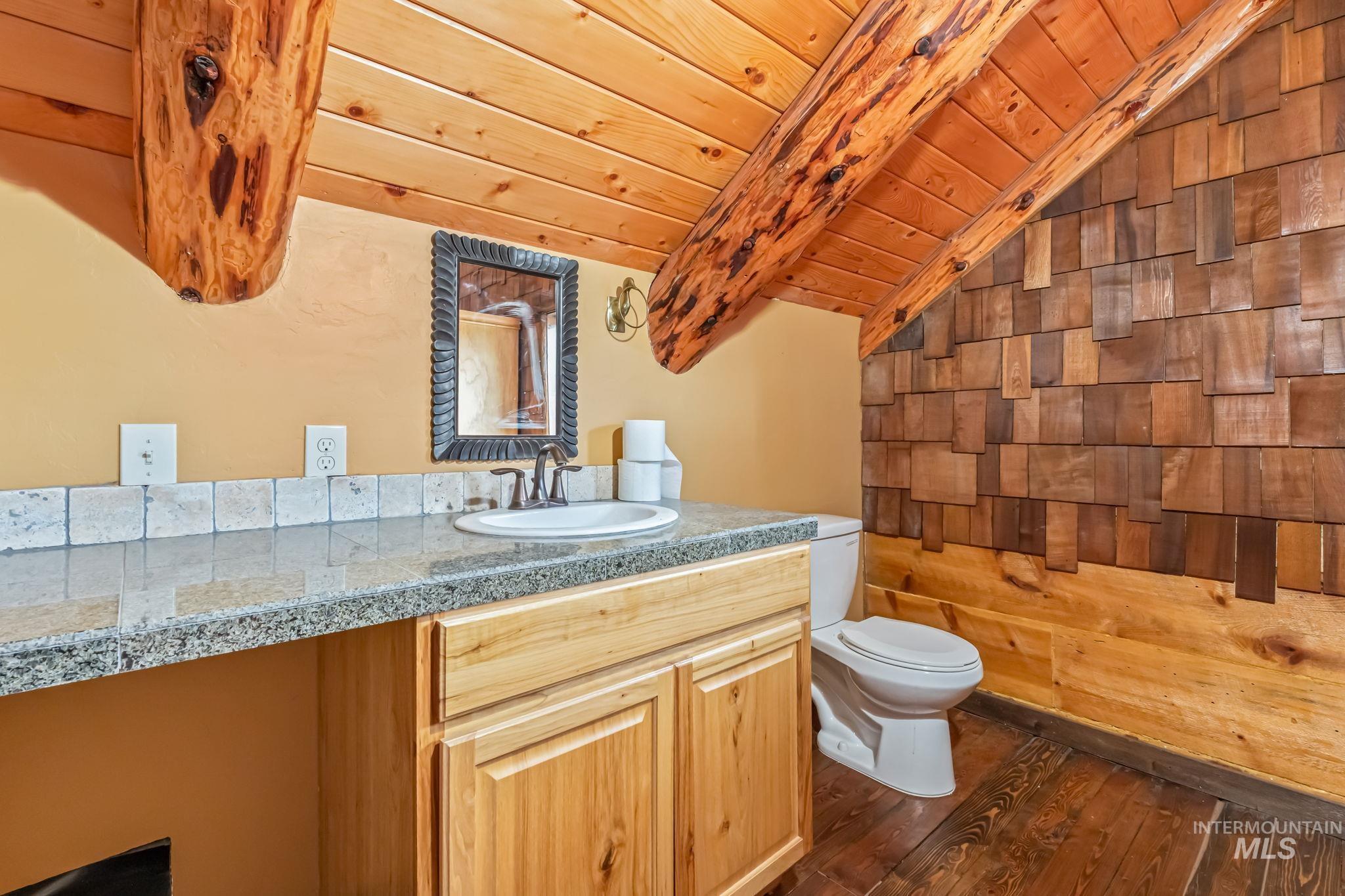 15 Rim Canyon Lane Boise, ID 83716 - Photo 19 of 31 Half bathroom with vanity, vaulted ceiling with beams, dark wood-type flooring, wooden walls, and wood ceiling