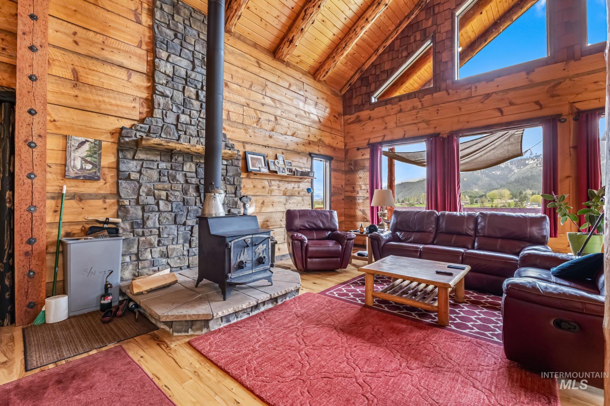 15 Rim Canyon Lane Boise, ID 83716 - Photo 6 of 31 Living room with hardwood / wood-style floors, a high wood beamed ceiling, wood walls, a wood stove, and a mountain view