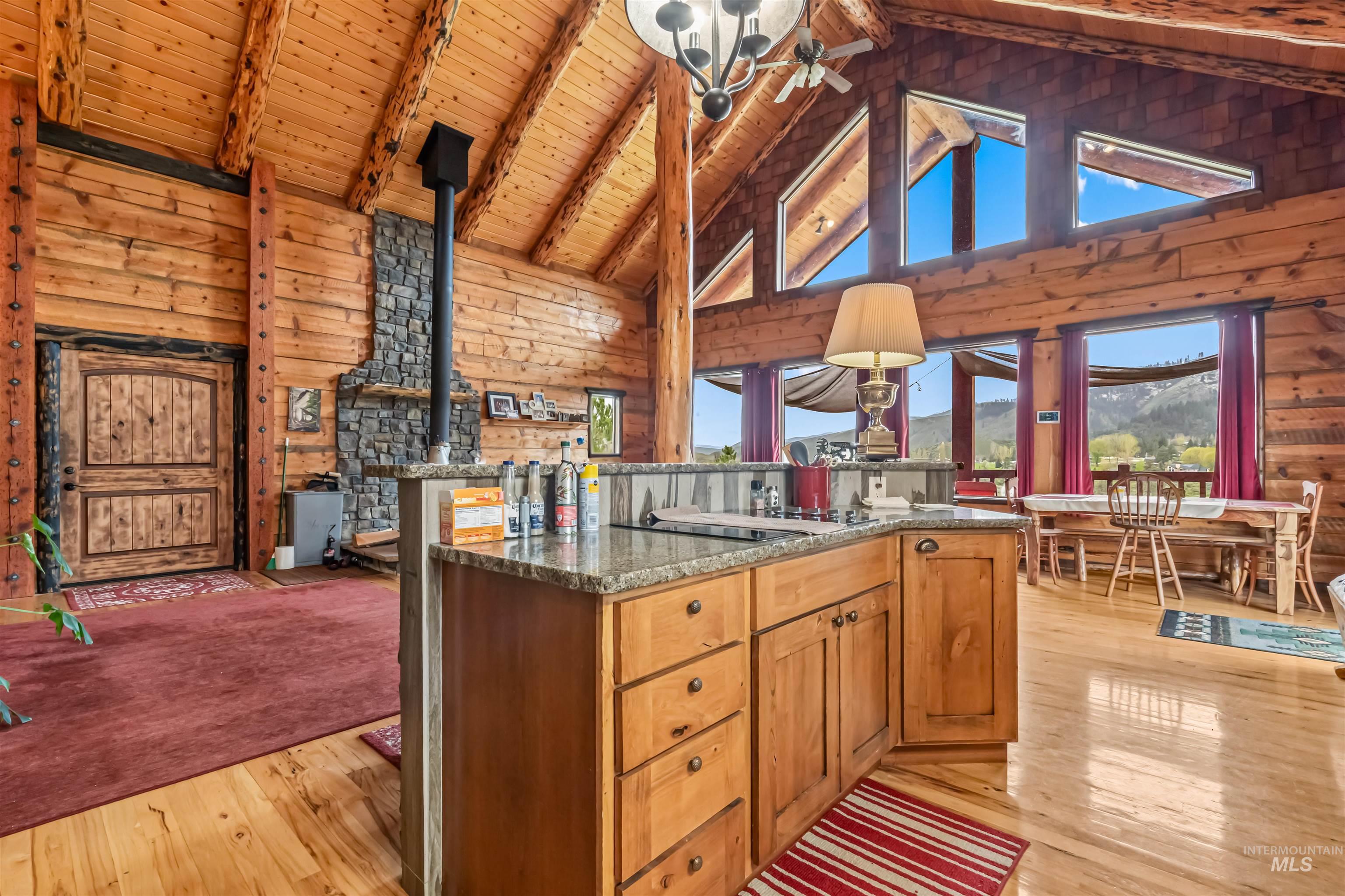 15 Rim Canyon Lane Boise, ID 83716 - Photo 8 of 31 Kitchen featuring wood walls, light wood-type flooring, wood finish cabinets, a center island, and a high wooden beamed ceiling