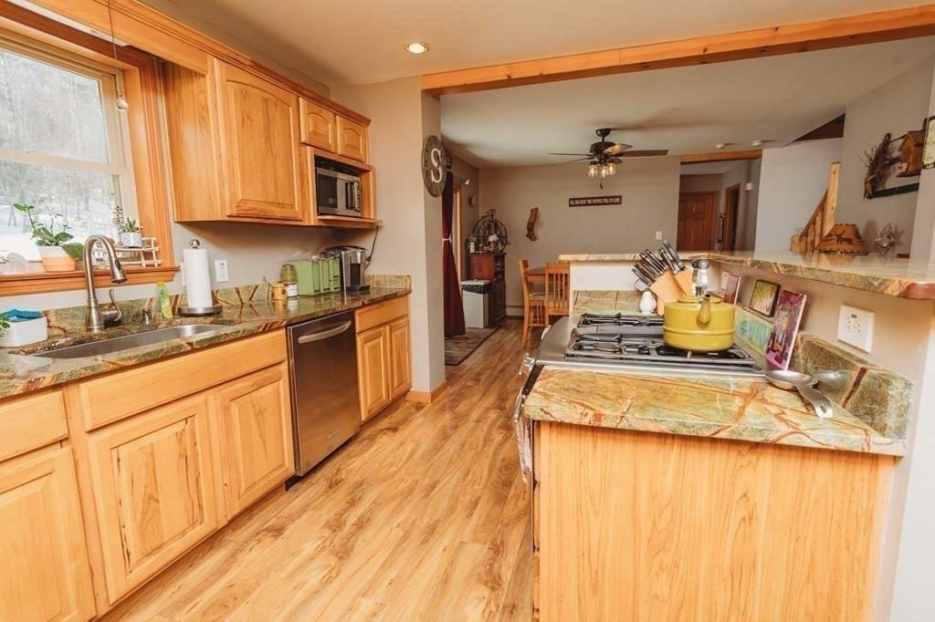 123 Davis Mine Road Rowe, MA 01367 - Photo 13 of 41 a kitchen with stainless steel appliances granite countertop a sink dishwasher stove and microwave with wooden cabinets