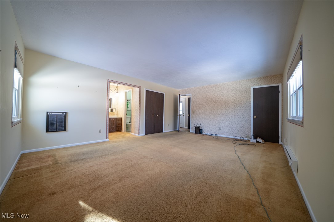 11702 Clark Road Chardon, OH 44024 - Photo 15 of 29 Primary bedroom with ensuite bath, carpet floors, baseboard heating, and an accent wall
