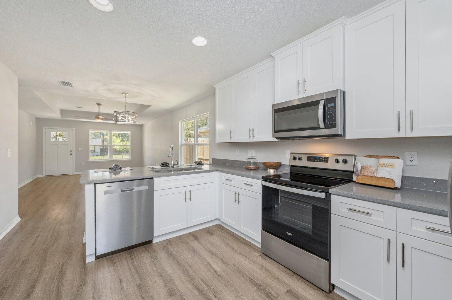 3161 Haskell Langley Road Crestview, FL 32539 - Photo 11 of 36 a kitchen with stainless steel appliances granite countertop a stove top oven a sink dishwasher and white cabinets with wooden floor