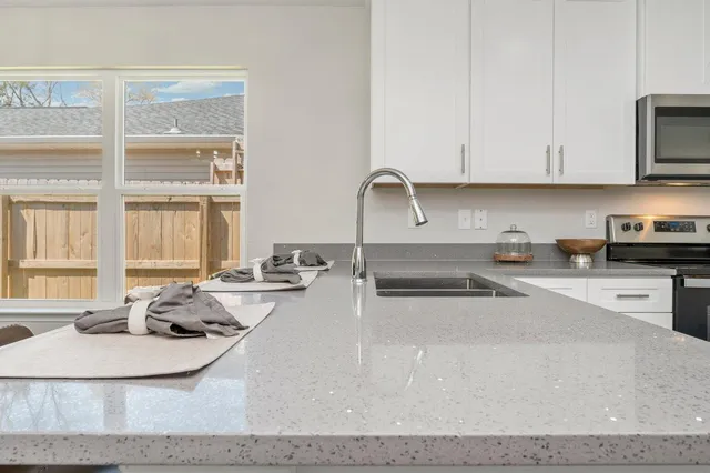 a kitchen with stainless steel appliances granite countertop a sink a stove and white cabinets