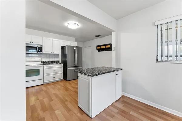 a kitchen with stainless steel appliances white cabinets and wooden floor