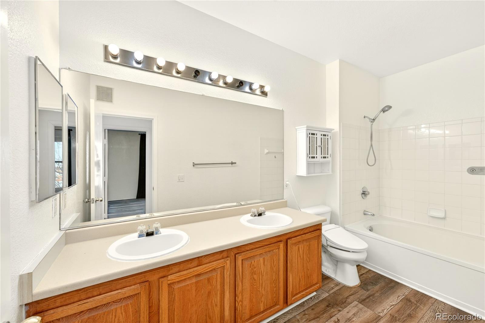 18929 East Warren Circle, Unit C205 Aurora, CO 80013 - Photo 22 of 46 a spacious bathroom with a double vanity sink double mirror bathtub shower and a toilet