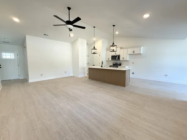 an empty room with kitchen appliances and a ceiling fan