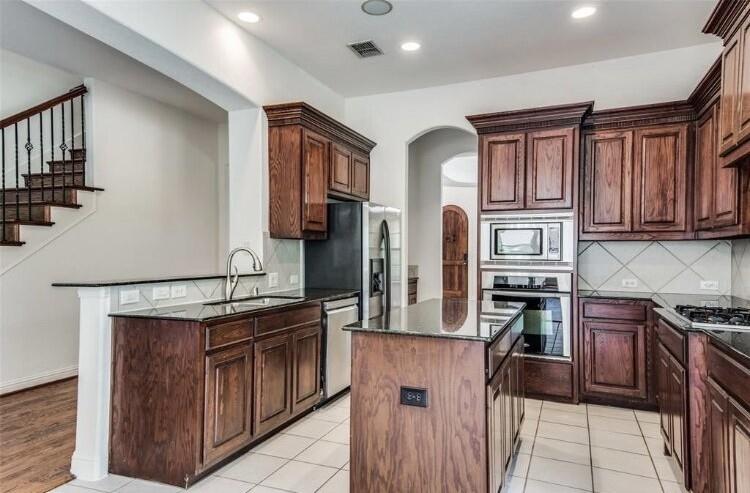 6821 Camino Rio Irving, TX 75039 - Photo 9 of 20 a kitchen with stainless steel appliances granite countertop a stove top oven a sink dishwasher and a refrigerator