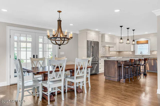 a dining room with stainless steel appliances kitchen island granite countertop a dining table chairs and chandelier