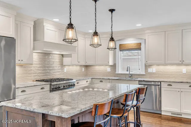 a kitchen with stainless steel appliances granite countertop a stove a sink a refrigerator a stove and white cabinets