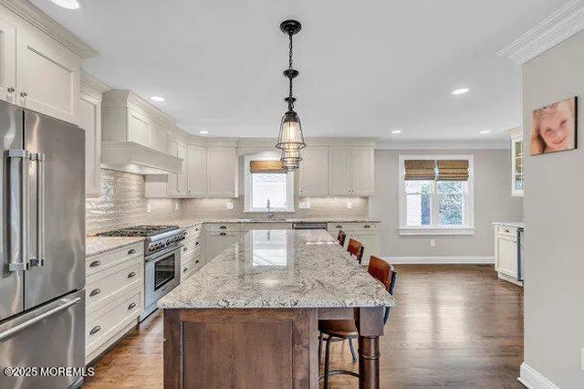 a kitchen with stainless steel appliances granite countertop a sink a stove and refrigerator