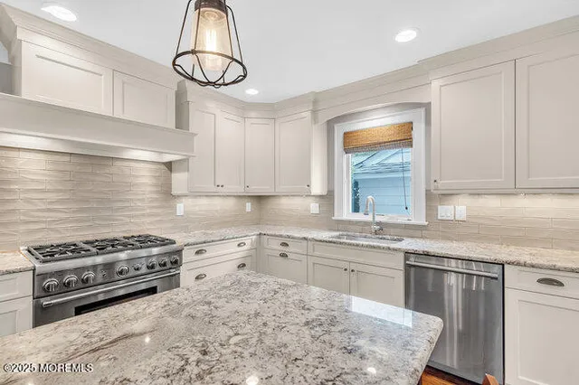 a kitchen with granite countertop a sink cabinets stainless steel appliances and a window