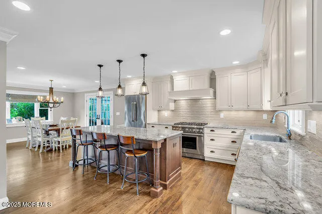 an open kitchen with granite countertop a stove top oven a sink a dining table and chairs