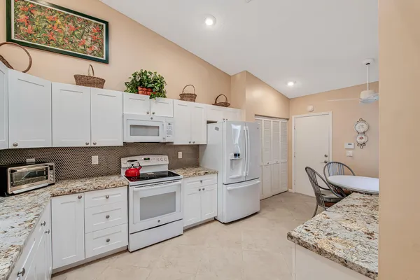 a kitchen with white cabinets and appliances