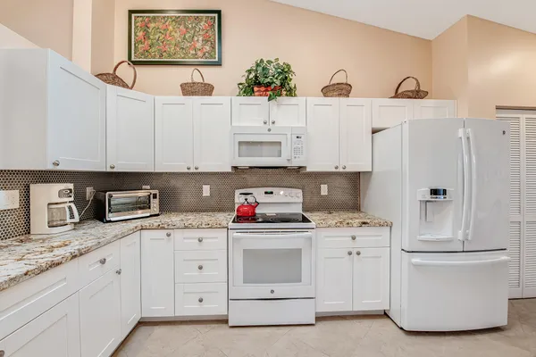 a kitchen with white cabinets and white appliances