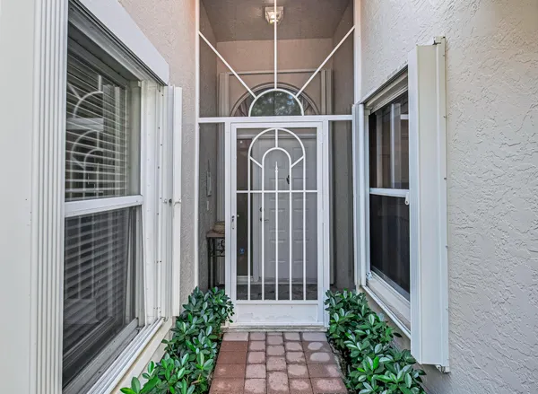 a view of a house with a wooden door and potted plants