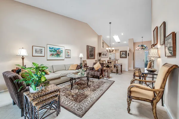 a living room with furniture potted plant and kitchen view